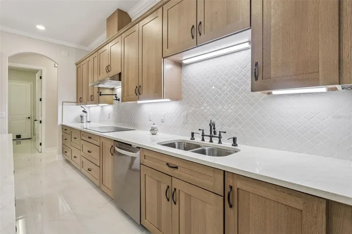 Wall-to-wall cabinetry and expansive quartz counters give you serious prep space—plus a built-in pot filler at the cooktop and a designer tile backsplash with under-cabinet lighting for that crisp, high-end finish.