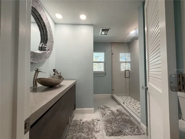 Guest bathroom featuring a walk-in shower and updated finishes.