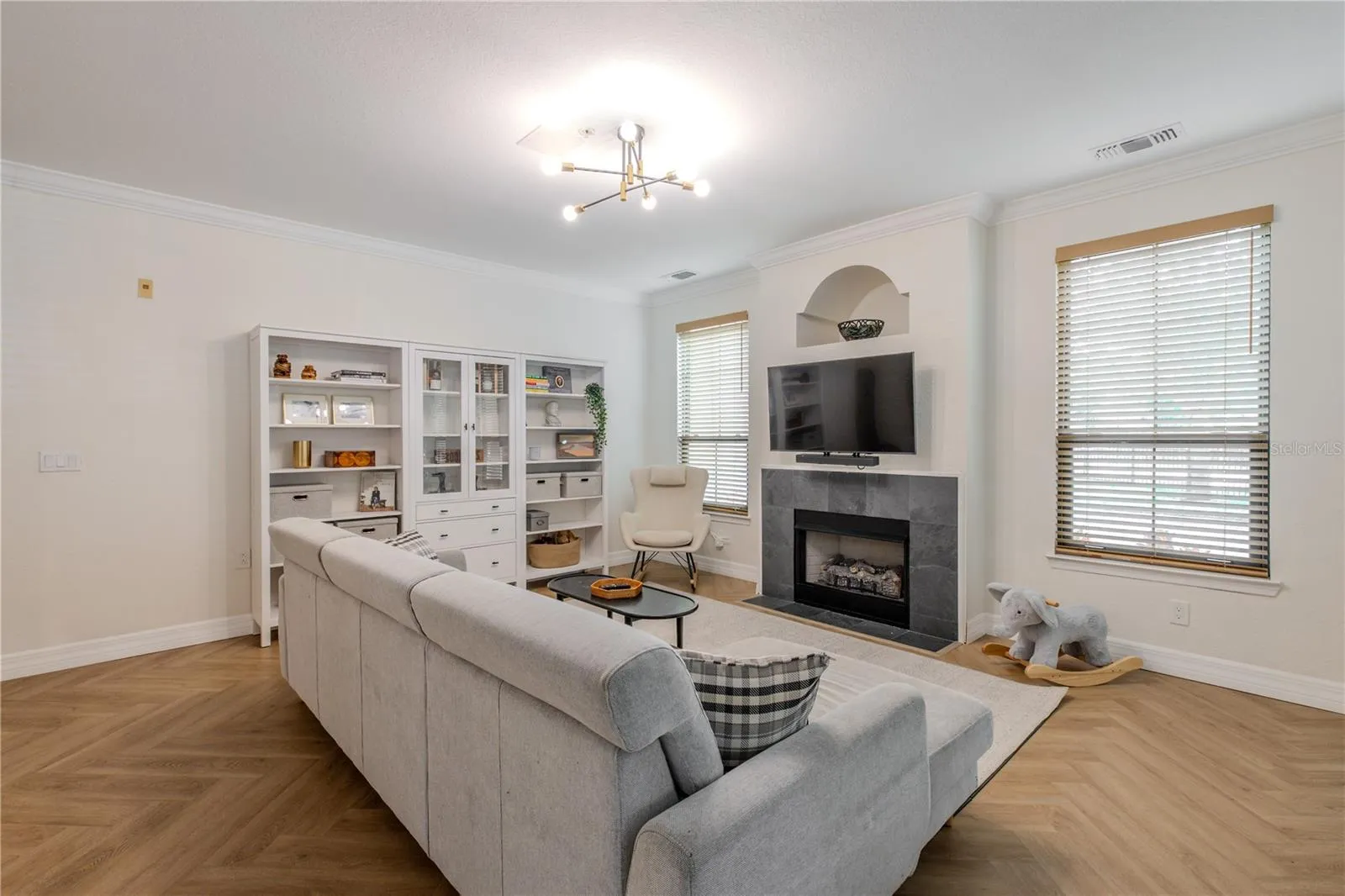 Additional view of the spacious open-concept living area with chevron luxury vinyl plank flooring, a modern fireplace, and seamless flow into the dining space beyond.