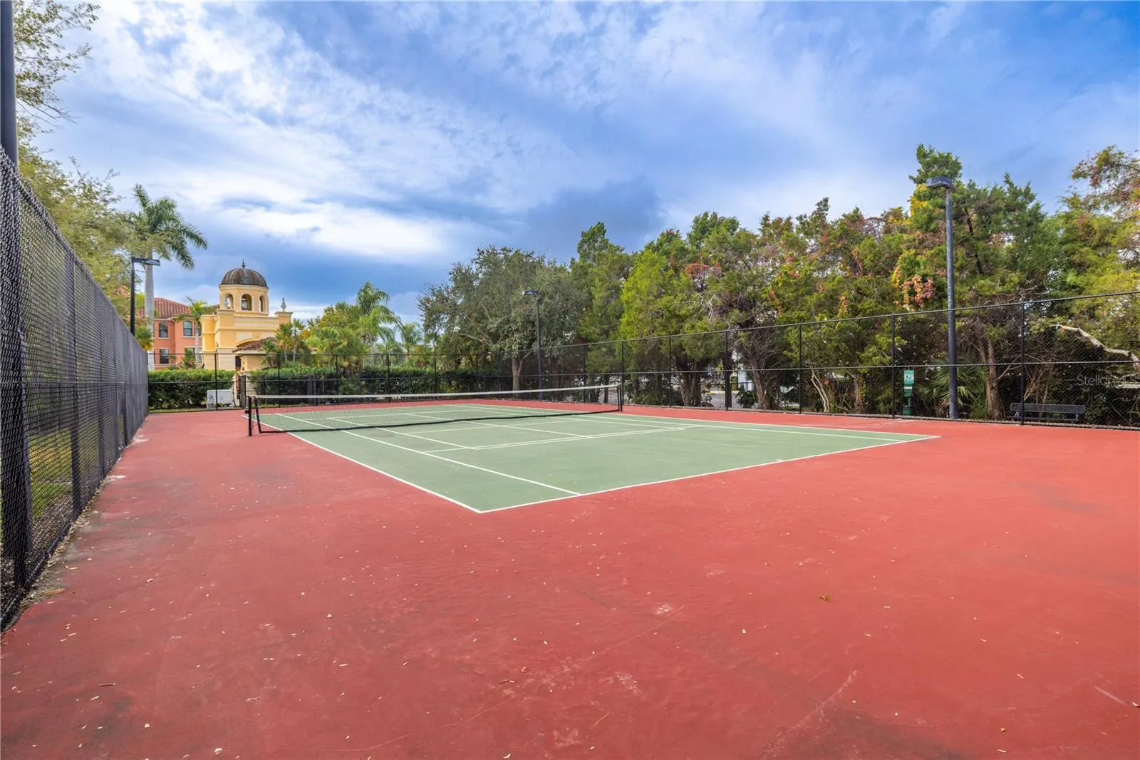 Angled ground view of the beautifully maintained tennis court.