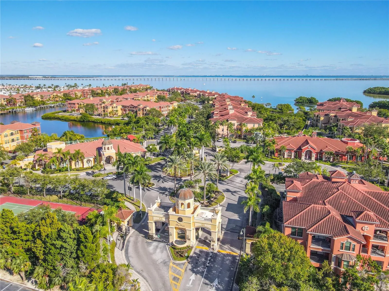 Another sweeping aerial views showcase the vibrant Mediterranean-style community set against sparkling bay waters and an iconic bridge backdrop, from the secured entry gates capturing the essence of relaxed waterfront living.