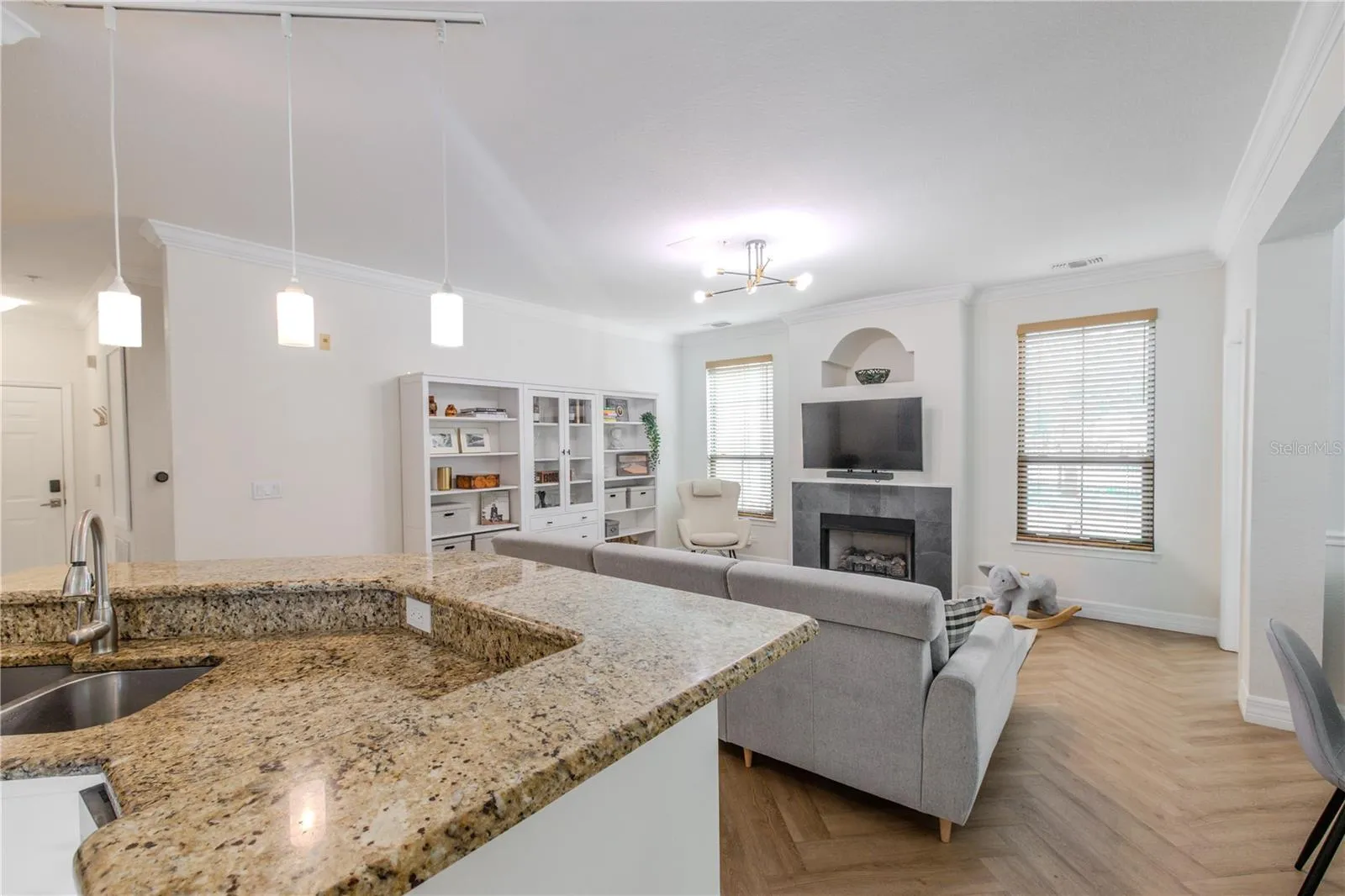 This open-concept kitchen with granite peninsula over looks the living area, showcasing seamless flow, warm finishes, and abundant natural light.