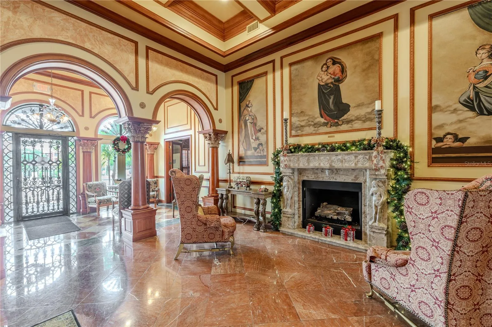 Additional view of the grand clubhouse lounge features soaring coffered ceilings, dramatic murals and arched columns, gleaming marble floors, and an elegant fireplace seating area—offering a warm, truly resort-style welcome.