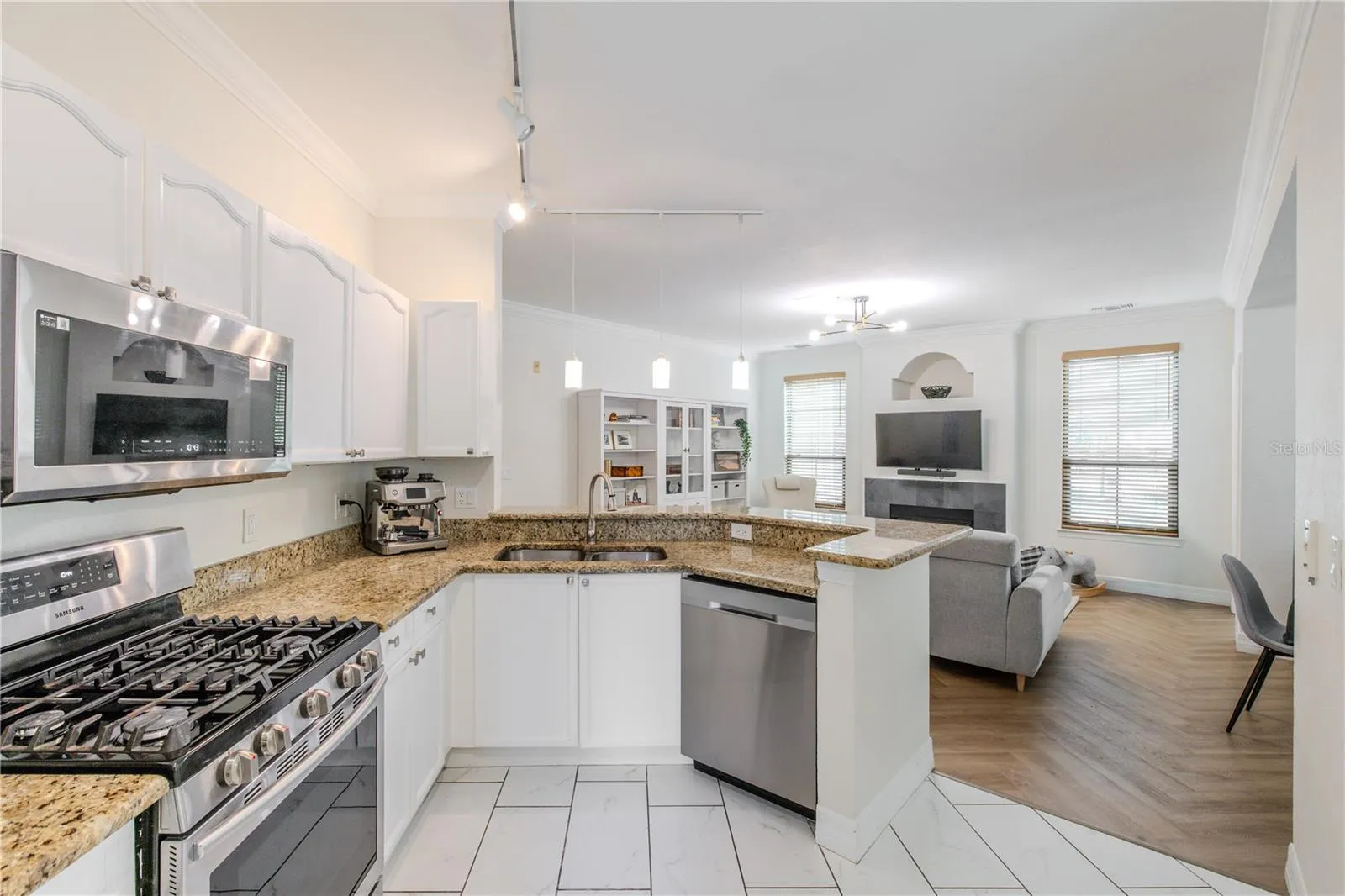 Raised-panel cabinetry wraps the space, creating a bright, cohesive look, while warm granite countertops provide generous prep and serving areas.