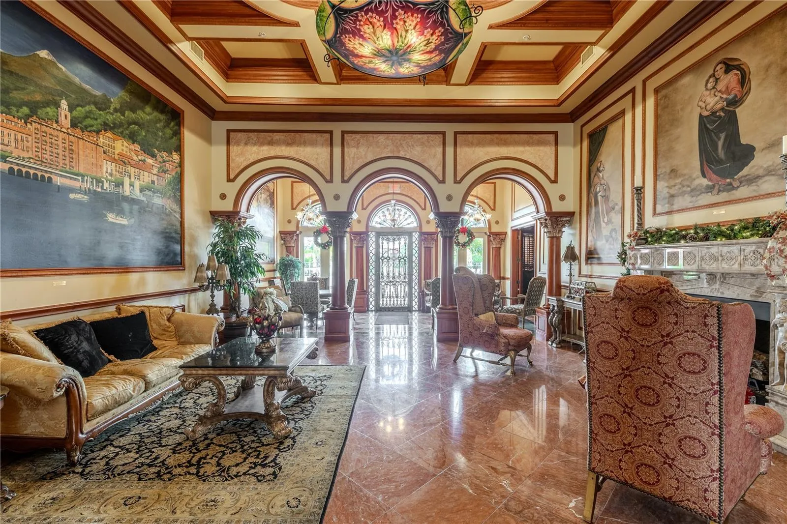 The grand clubhouse lounge features soaring coffered ceilings, dramatic murals and arched columns, gleaming marble floors, and an elegant fireplace seating area—offering a warm, truly resort-style welcome.