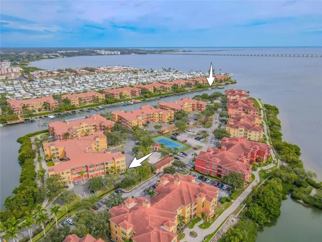 Another sweeping aerial views showcase the vibrant Mediterranean-style community set against sparkling bay waters and an iconic bridge backdrop, highlighting the condo and B60 boat slip while capturing the essence of relaxed waterfront living.
