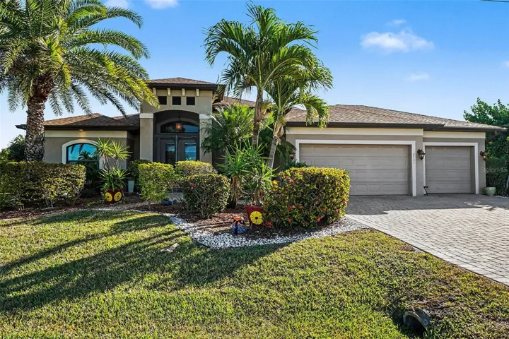 View of front of property with decorative driveway, a garage, stucco siding, and a front yard