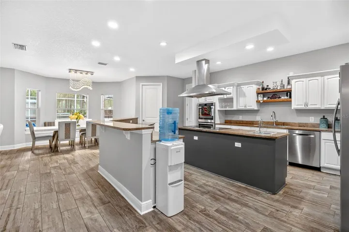 Stunning bright open-concept chef’s kitchen centerpiece with expansive island, quartz-style counters, stainless appliances, soft-close cabinetry, and seamless flow to the dining area and great room.