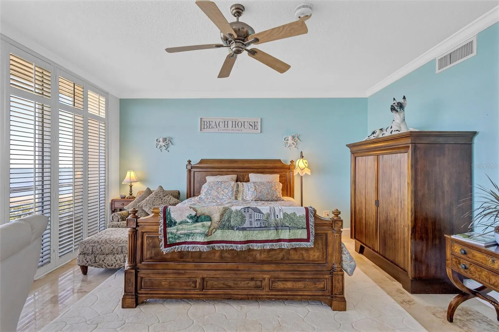 Primary bedroom with crown moldings, fluted, casings, and Plant blocks. Wall of windows with plantation shutters.