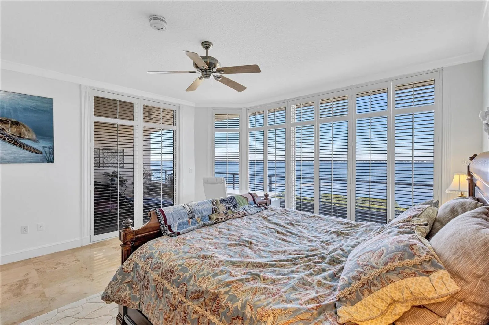 Primary Bedroom with access to the East Bay View Balcony and Travertine Floors and plantation Shutters