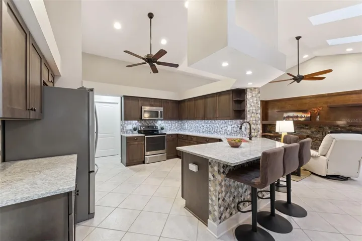 The heart of the home is the beautifully remodeled kitchen, featuring QUARTZ COUNTERTOPS, rich cabinetry, a BUILT-IN WINE FRIDGE, decorative backsplash, and upgraded STAINLESS STEEL APPLIANCES.