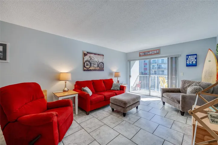 Comfortable living room with neutral tones, ample seating space, and direct balcony access, offering great natural light and a breezy, inviting atmosphere.