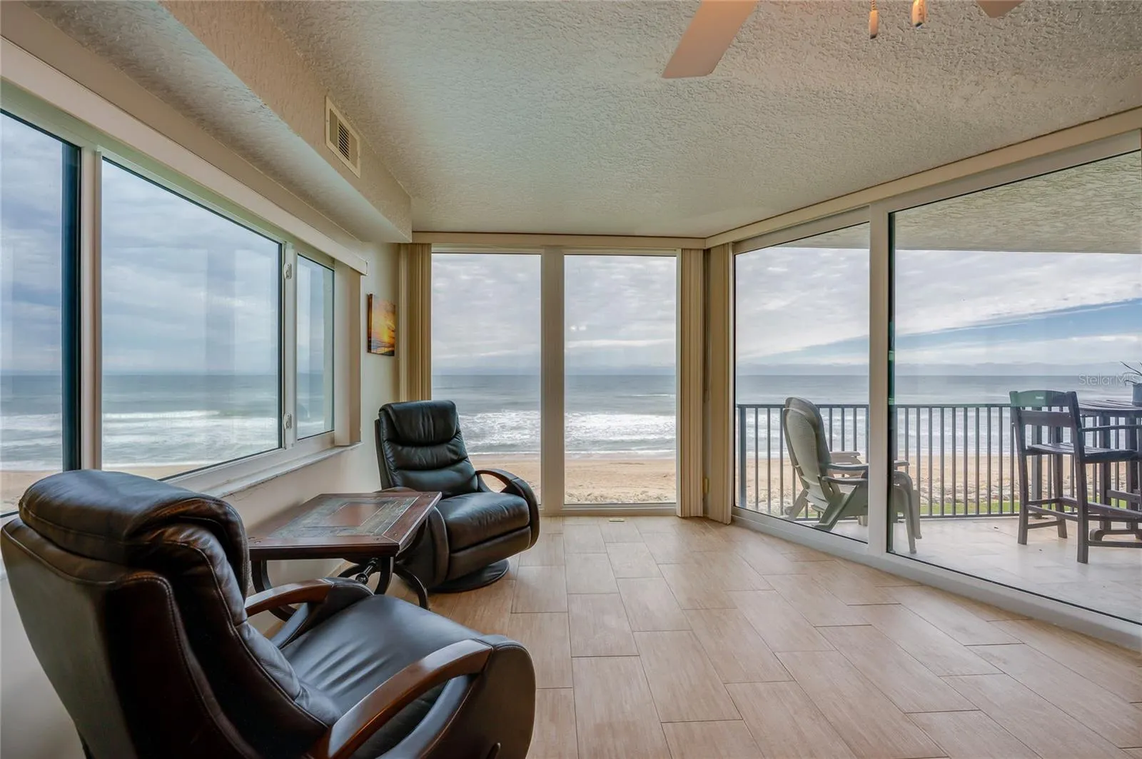 A light-filled corner retreat with panoramic ocean views through wraparound windows. This flexible space is perfect for morning coffee, reading, or enjoying the serene beachfront setting.