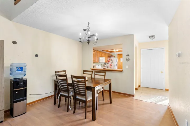 Bright dining area with a chandelier, open sightlines to the kitchen with a breakfast bar seating, and open flow to the living space.