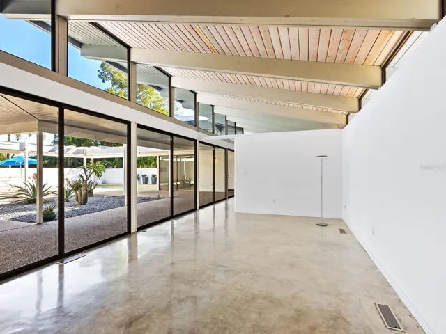 Walking into first living room area you see through sliding walls of glass toward courtyard and pool beyond