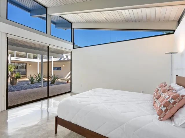 Primary bedroom looking out to gardens and courtyard with dramatic clerestory windows show above