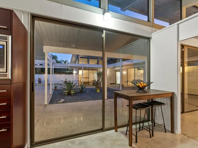 Kitchen looking out at courtyard, pool and rooms at dusk