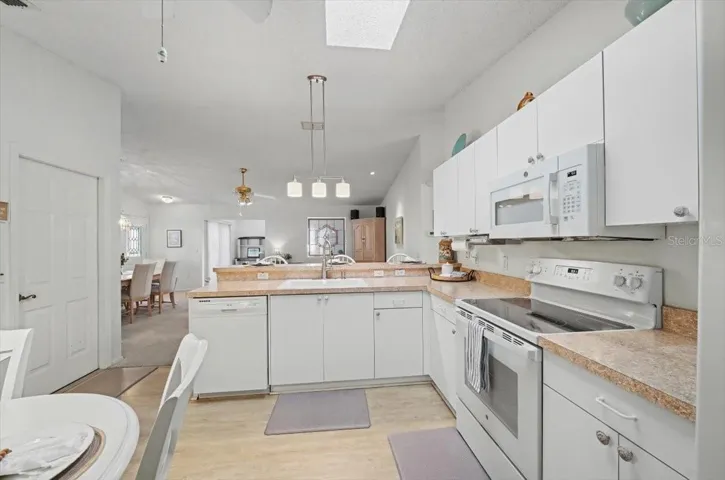Kitchen is ready for you, with dishes, utensils, pots and pans, and beautiful white cabinets and neutral tones