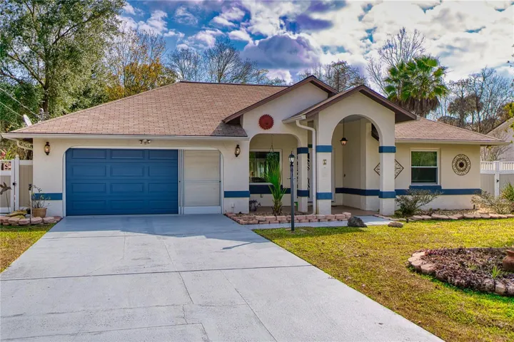 Inviting curb appeal with a wide driveway, oversized two-car garage, and a charming arched front entry—framed by mature trees and a fenced yard for extra privacy.