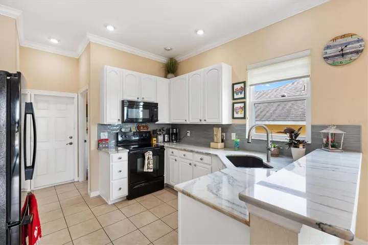 Kitchen with QUARTZ counter tops, backsplash, crown molding, tile floors, closed door leads to garage, door to right of the closed door is the laundry room.