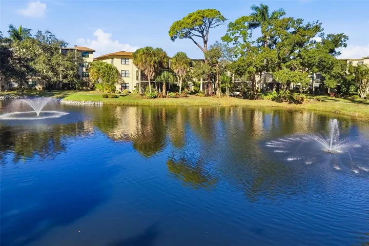 Pond Reflection ViewPicturesque pond with fountains and surrounding greenery creating a peaceful atmosphere