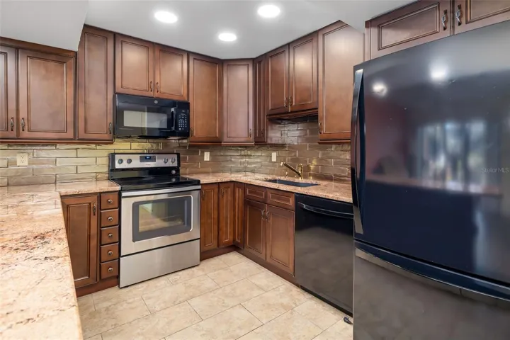 Updated kitchen with wood cabinetry, granite countertops, and stainless steel appliances in this Bradenton condo