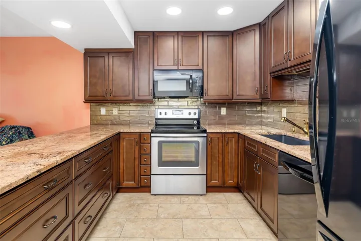 Granite countertops, tile backsplash, and ample cabinet storage in updated kitchen