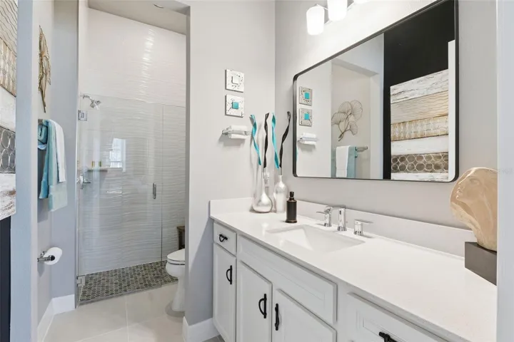 Gorgeous Private  Bath with Quartz Counter, Upgraded Cabinets and Mirror plus Rectangular Undermount Sink. The Shower instead of a Tub has Seamless Doors, Modern Tile to the Ceiling and decorative Tile Floor!