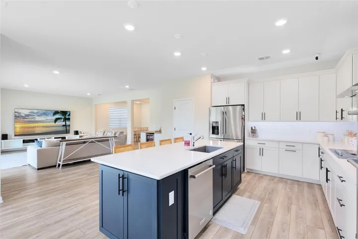 Chef’s kitchen with crisp white quartz countertops, KitchenAid gourmet stainless appliances, 42” soft-close cabinets and drawers, a large granite island with a large granite sink, and an oversized walk-in pantry.