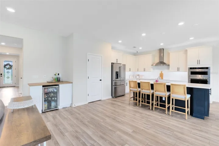Chef’s kitchen with crisp white quartz countertops, KitchenAid gourmet stainless appliances, 42” soft-close cabinets and drawers, a large granite island with a large granite sink, and an oversized walk-in pantry.