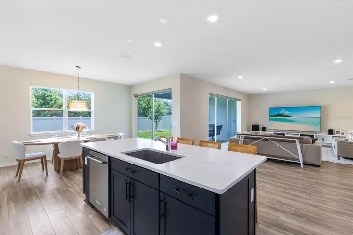 Chef’s kitchen with crisp white quartz countertops, KitchenAid gourmet stainless appliances, 42” soft-close cabinets and drawers, a large granite island with a large granite sink, and an oversized walk-in pantry.