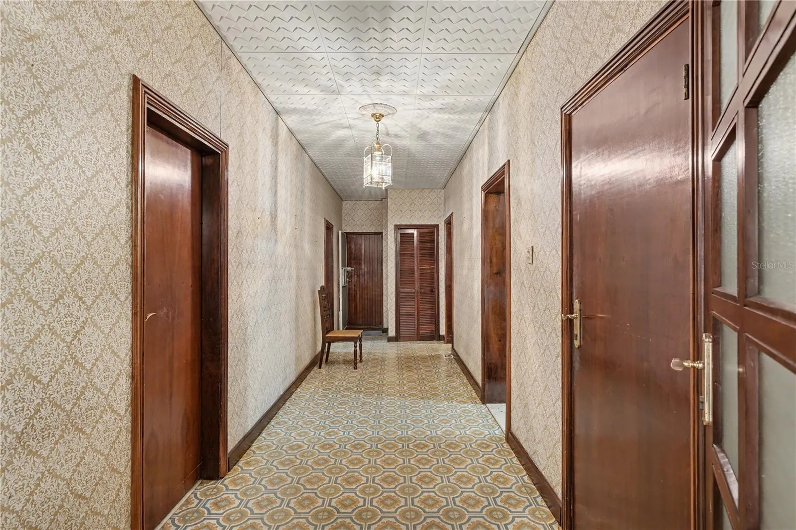Central hallway showcasing original doors, ceiling detail, and patterned tile flooring.