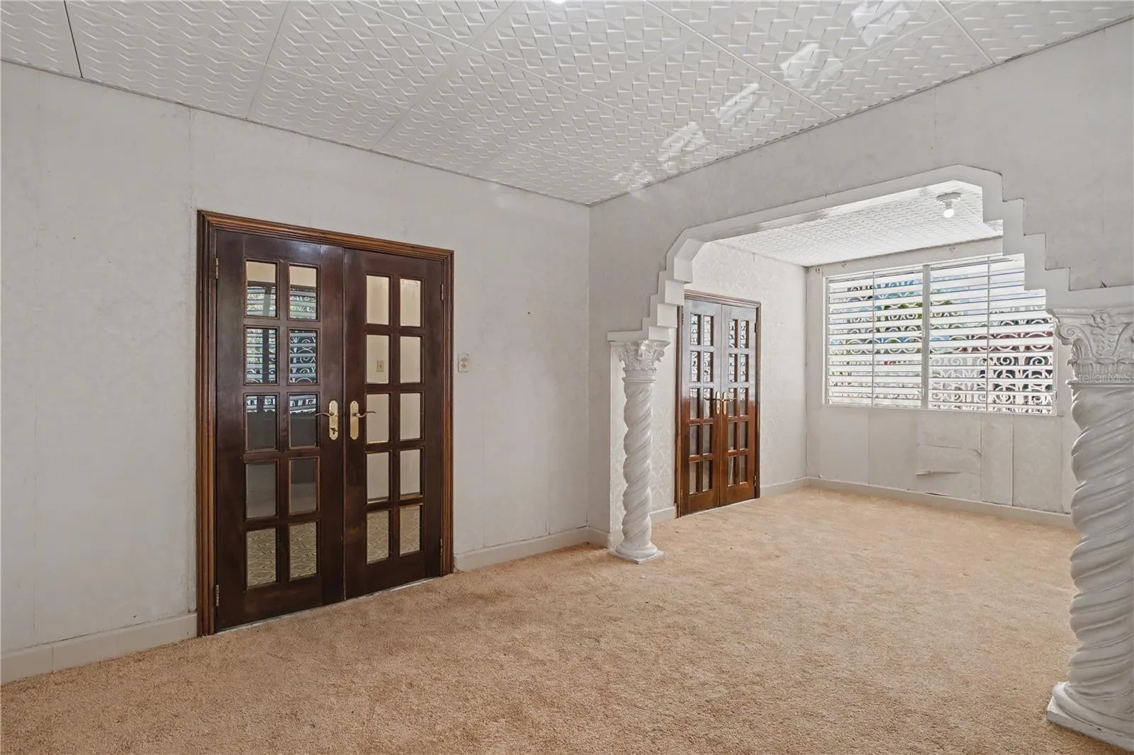 Spacious living and dining  area featuring original archway and timeless architectural character.