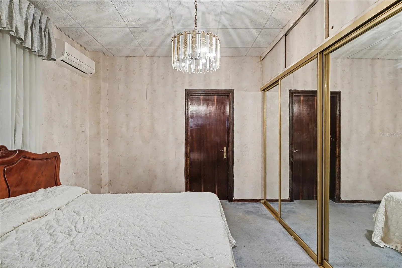 Bedroom featuring mirrored closets and a classic chandelier, well-proportioned and adaptable.