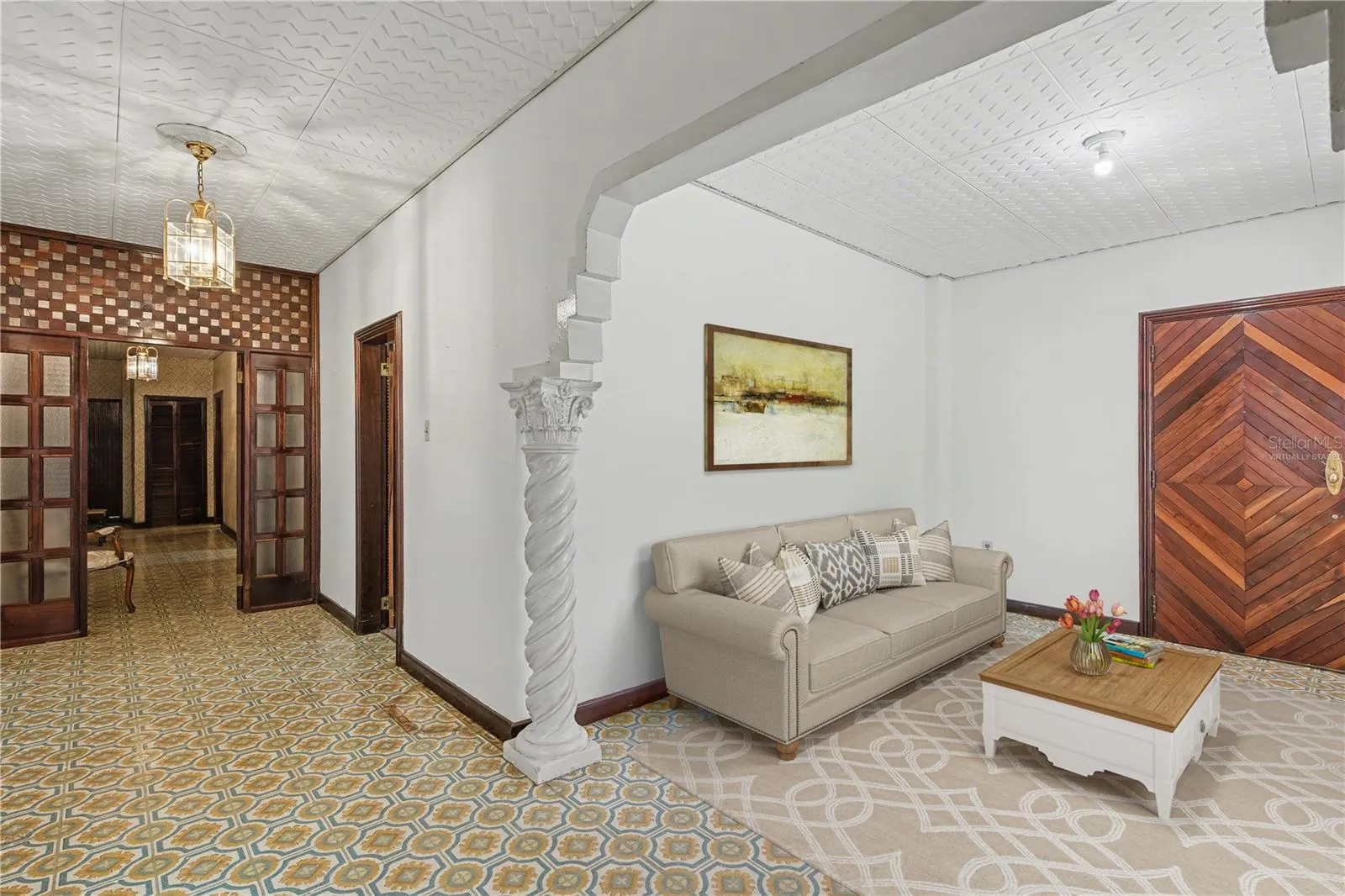 Open living area with preserved architectural flow and tile details. Virtually staged.