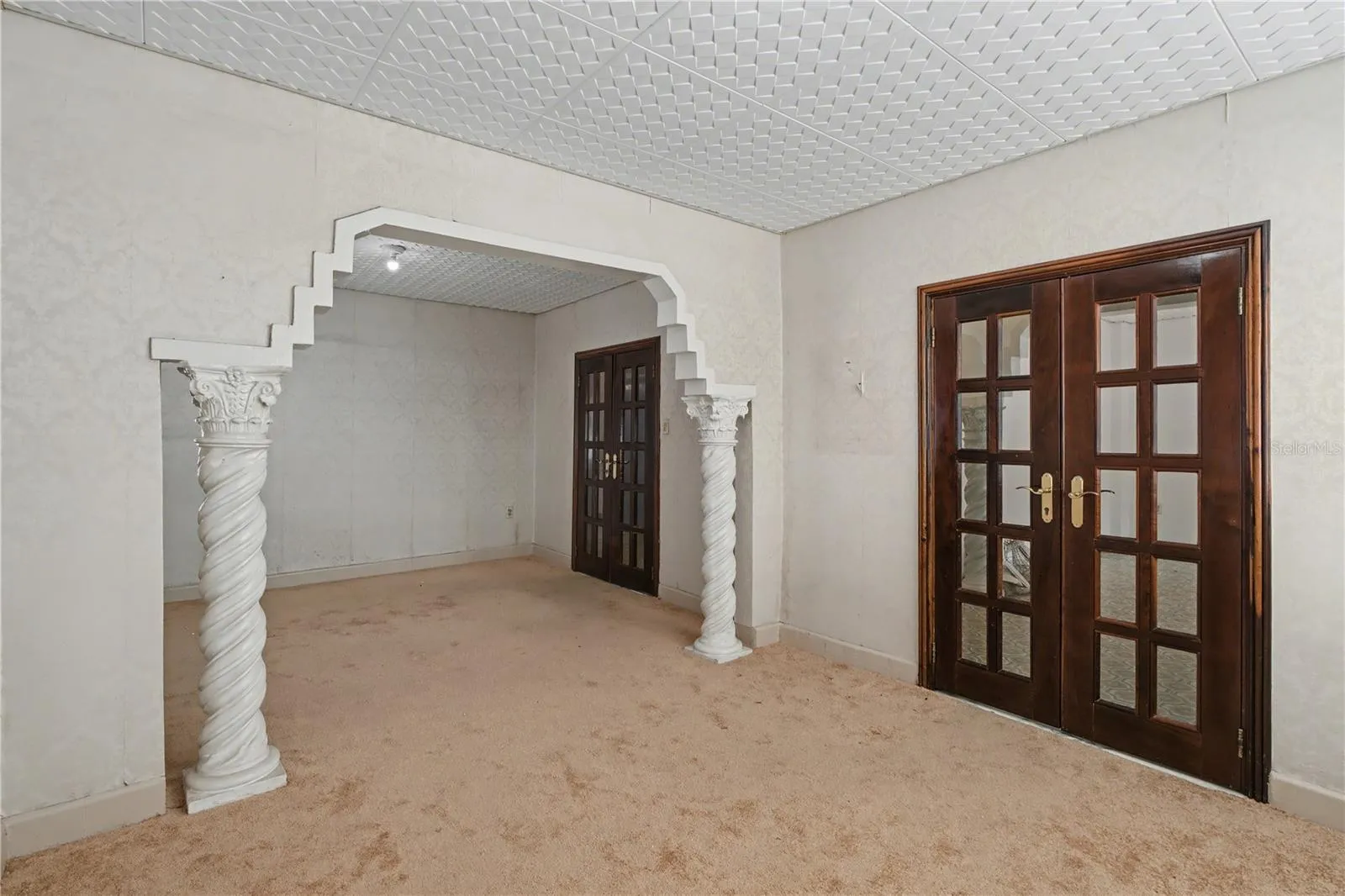 Living and dining areas connected by a classic interior arch with spiral columns.