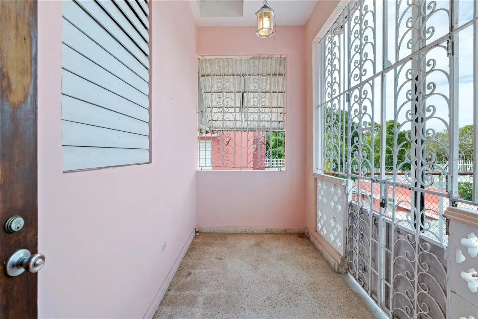 Enclosed gallery or porch with decorative ironwork and direct exterior connection.