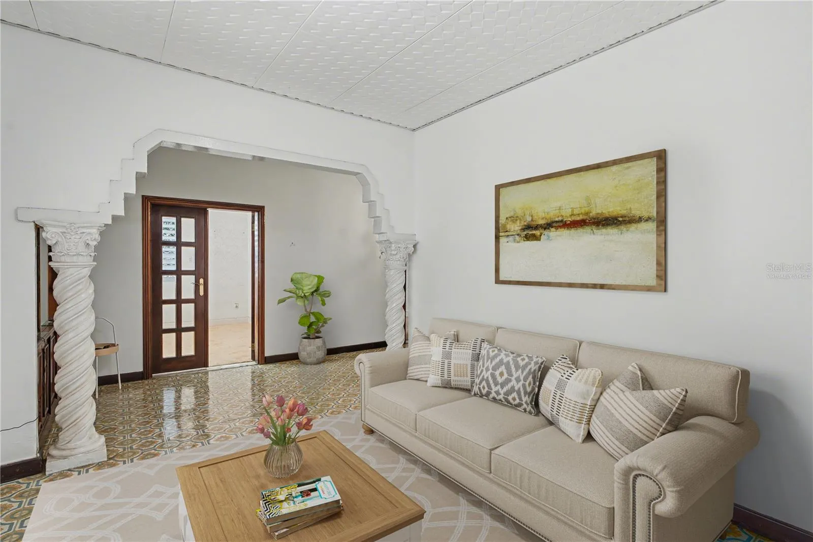 Formal living area historically used as an “anteroom,” showcasing preserved arches, columns, and classic tile floors. Virtually staged.