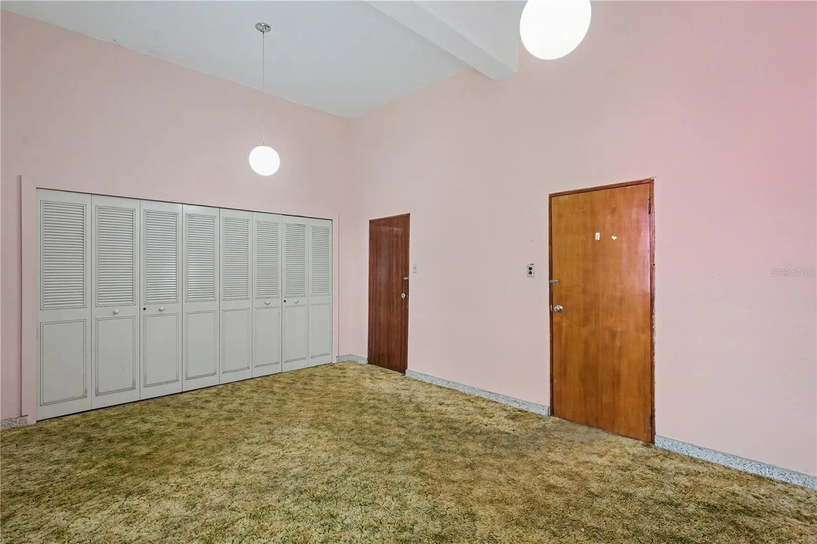 Alternate view of the primary bedroom highlighting original closets and generous proportions.