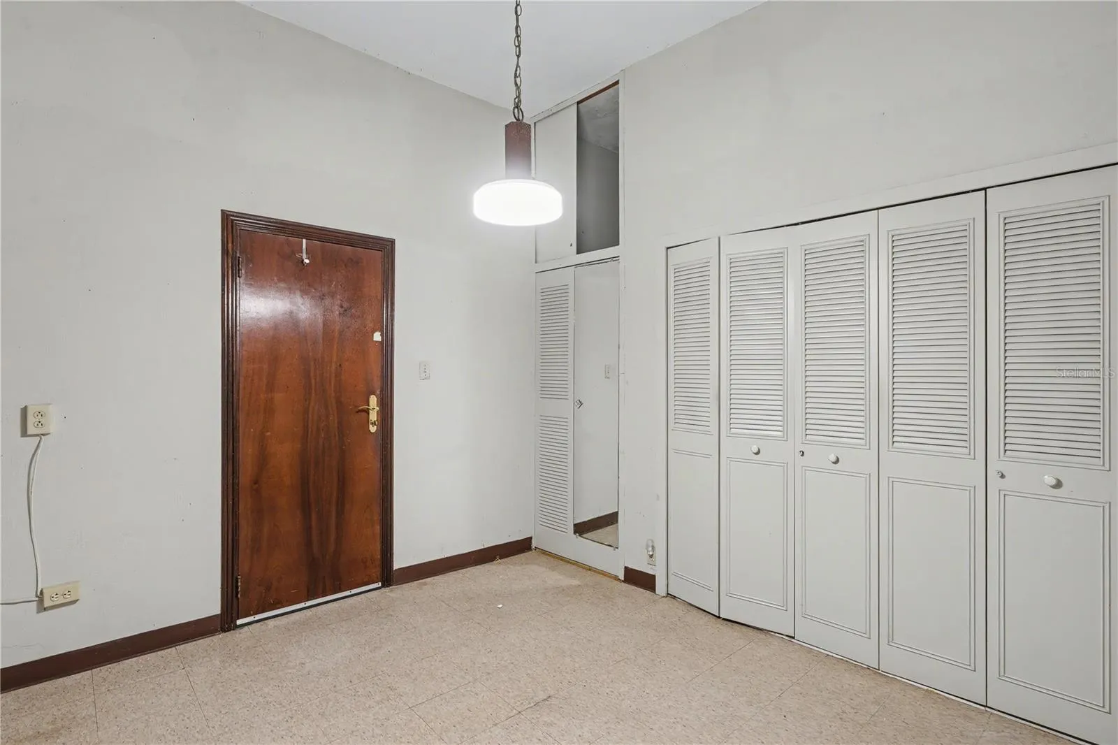 Bedroom with multiple closets and high ceilings, reflecting original scale and storage.