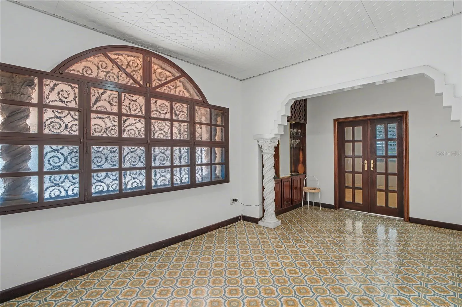 Original arched window with decorative glass enhancing natural light in the main living area.