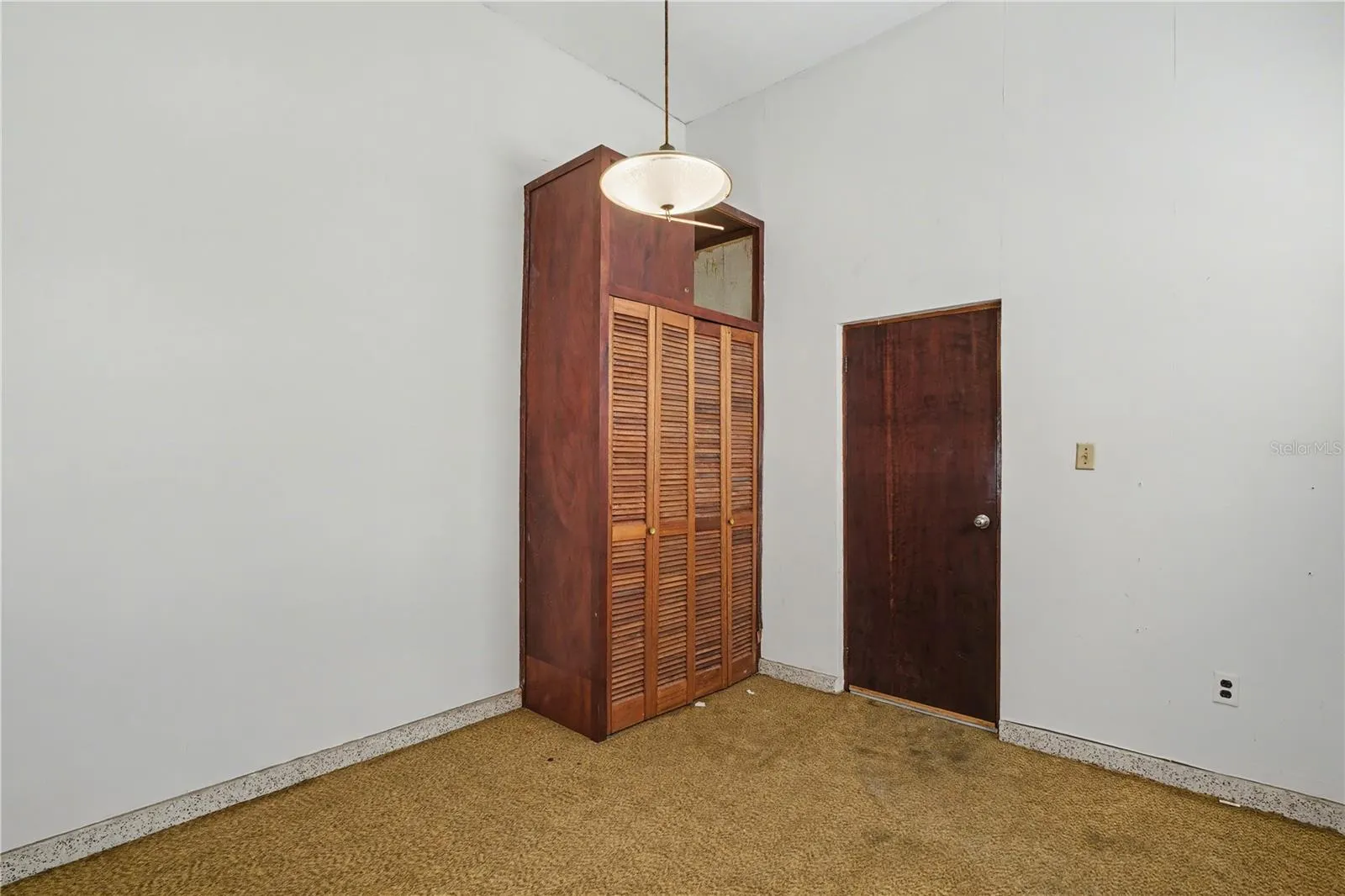 Bedroom with built-in wooden closets and high ceilings