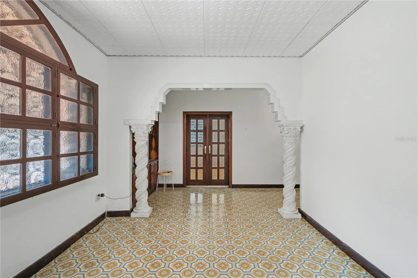 Architectural interior arch with spiral columns and patterned tile flooring.