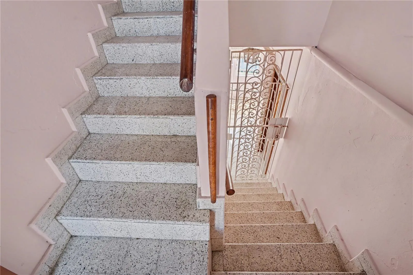 Central stairwell with terrazzo steps and wrought-iron security gate, providing controlled circulation between floors.