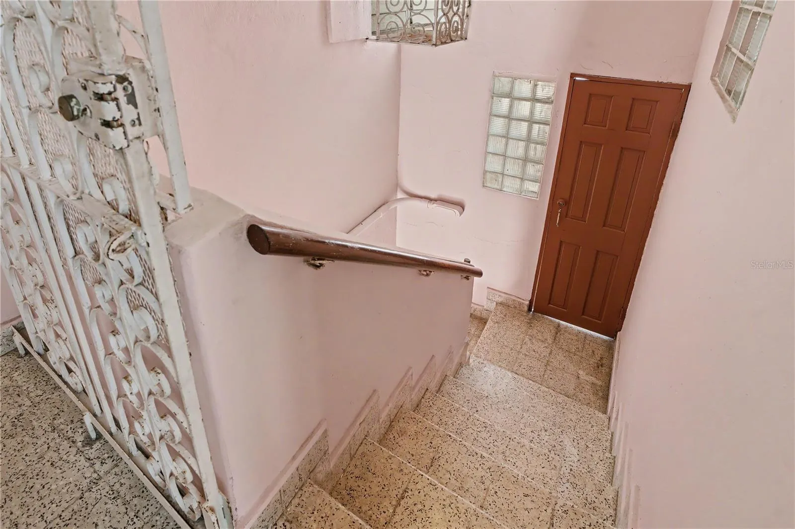 Stair landing with wrought iron gate and access to upper level