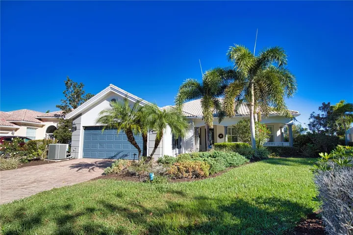 Inviting tile-roof home with lush, professionally designed landscaping, complemented by a paver driveway and walkways that enhance its resort-style curb appeal.