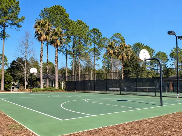 Community basketball court with sports field and lake behind it