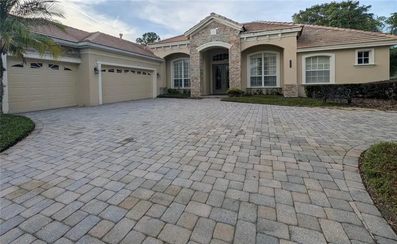 Impressive facade with stone details , paved driveway and Tile roof.