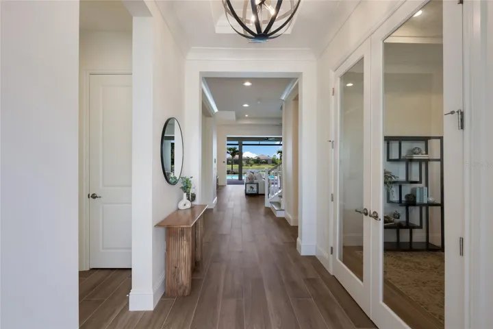 Front hallway with guest bed and full bath to the left and office and powder bath to the right