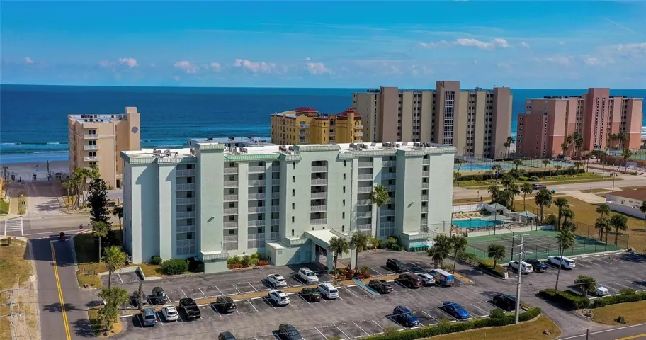 Aerial view of this well-maintained coastal condominium, ideally positioned just steps from the shoreline with convenient on-site parking and nearby amenities.